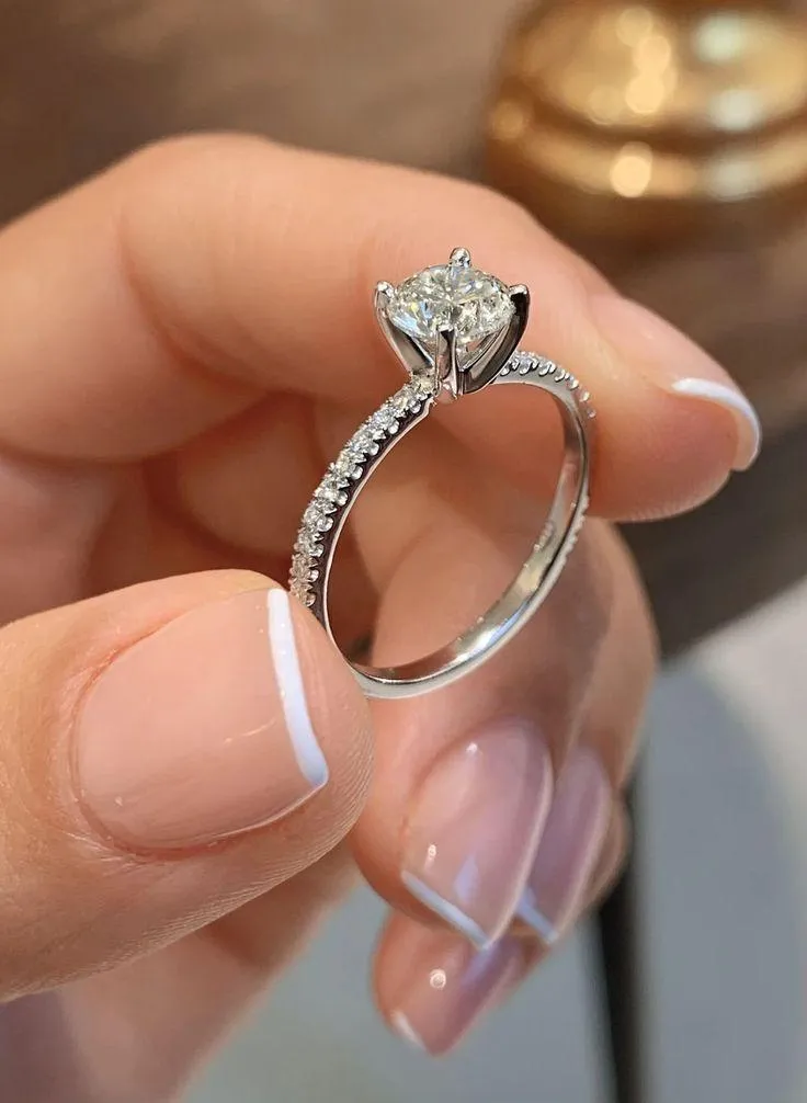 Elegant solitaire diamond ring with a sparkling round stone and slim silver band held in hand